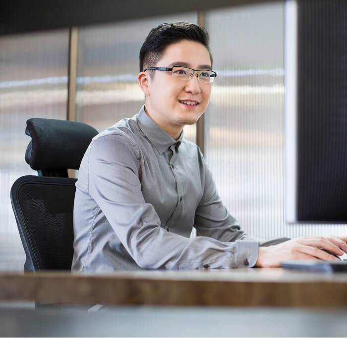 Person am Schreibtisch mit Monitor in einem modernen Büro